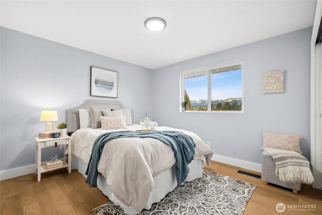 bedroom with visible vents, baseboards, and wood finished floors