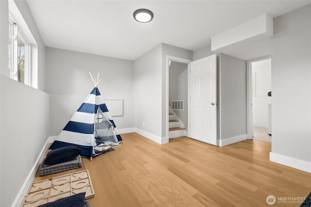 recreation room featuring visible vents, baseboards, and wood finished floors