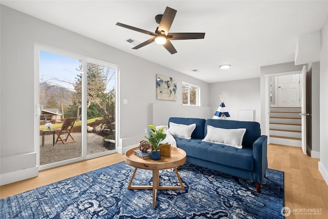 living room with stairway, baseboards, visible vents, and wood finished floors