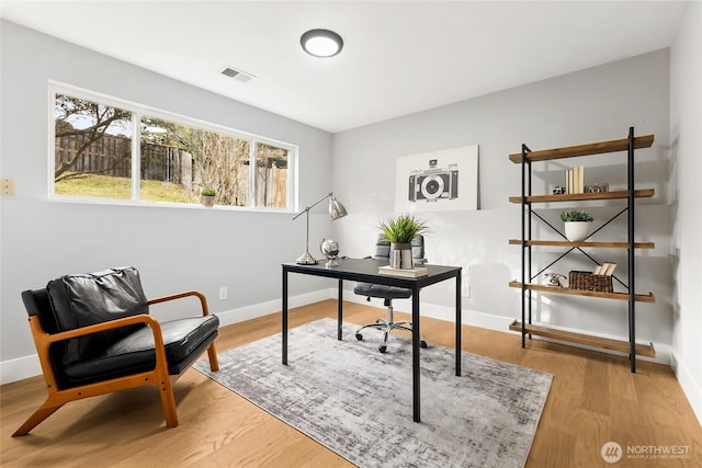 home office with light wood-type flooring, visible vents, and baseboards