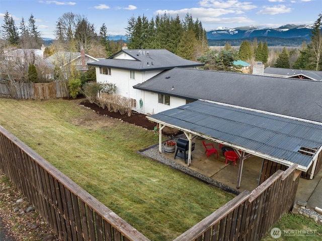 exterior space featuring metal roof, a mountain view, fence, a lawn, and a chimney