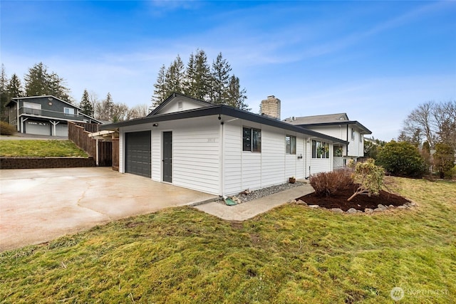 view of property exterior featuring a garage, a chimney, a lawn, and concrete driveway