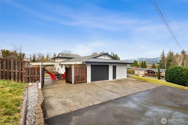 garage featuring driveway, fence, and a mountain view