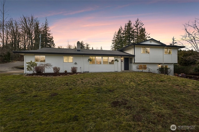 split level home with a chimney and a front yard