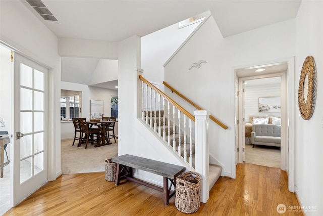 stairway featuring lofted ceiling, visible vents, baseboards, and wood finished floors