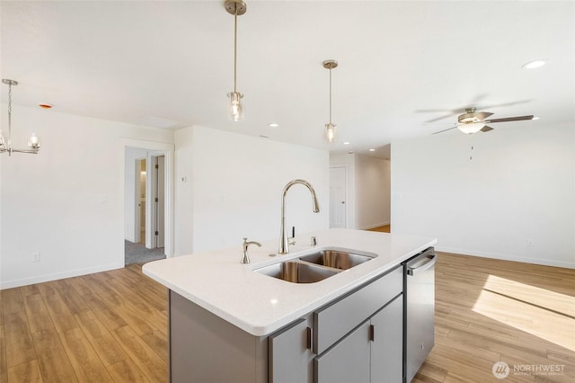 kitchen featuring open floor plan, an island with sink, light countertops, a sink, and dishwasher