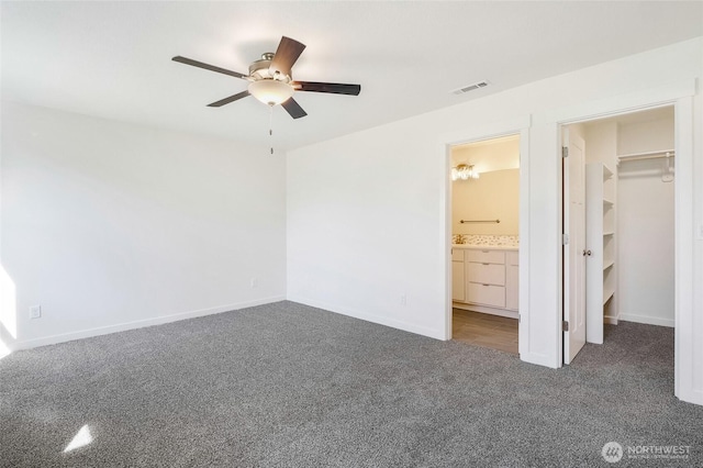 unfurnished bedroom featuring visible vents, a ceiling fan, baseboards, a walk in closet, and carpet flooring