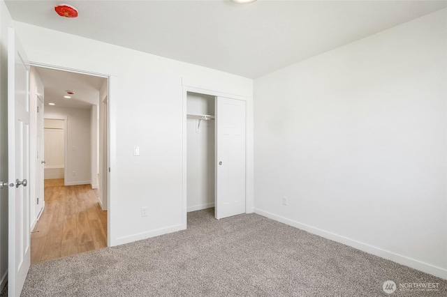 unfurnished bedroom with baseboards, light carpet, and a closet