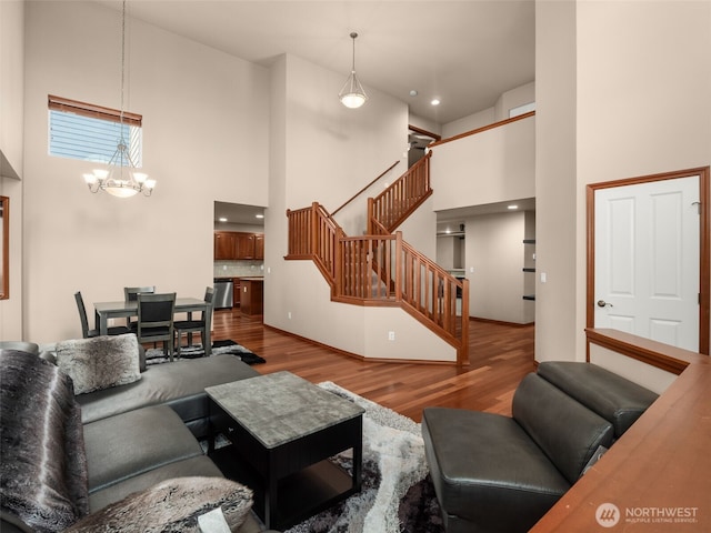 living room featuring a chandelier, wood finished floors, a towering ceiling, and stairs