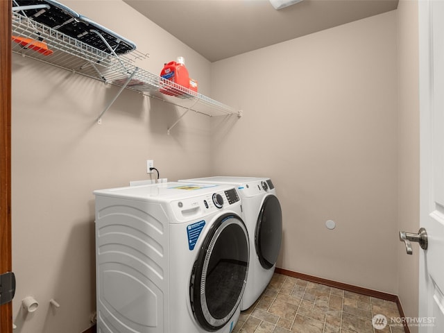 washroom featuring laundry area, stone finish floor, washer and clothes dryer, and baseboards