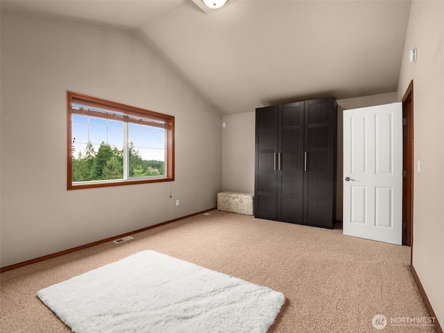 carpeted bedroom featuring lofted ceiling, visible vents, and baseboards