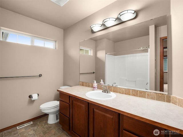 bathroom with toilet, vanity, visible vents, a shower, and stone finish floor