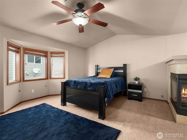 bedroom featuring lofted ceiling, carpet, baseboards, and a tile fireplace