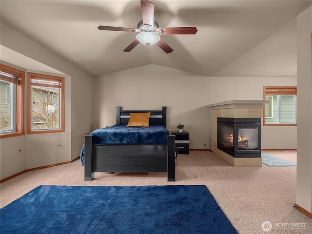 carpeted bedroom with lofted ceiling, ceiling fan, baseboards, and a tile fireplace