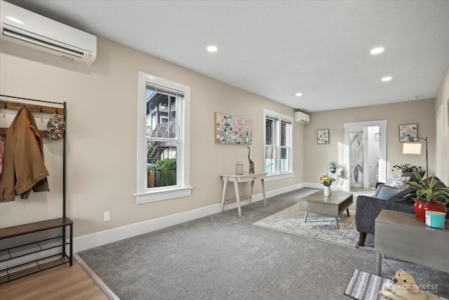 living area with baseboards, a wall mounted AC, and a healthy amount of sunlight