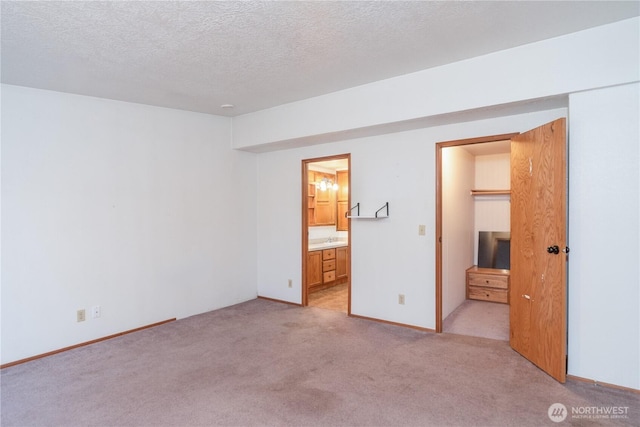 6612 NE Pear St, Suquamish, WA 98392 - unfurnished bedroom featuring a textured ceiling, ensuite bathroom, light colored carpet, a sink, and baseboards