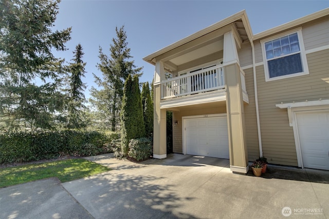 view of front of home featuring concrete driveway, an attached garage, and a balcony