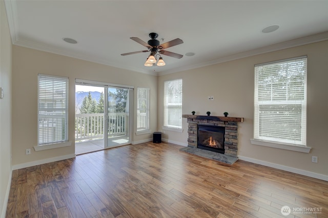 unfurnished living room with a ceiling fan, a stone fireplace, wood finished floors, and ornamental molding