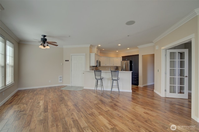 unfurnished living room featuring crown molding, a ceiling fan, baseboards, and light wood finished floors