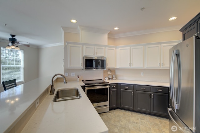 kitchen with ornamental molding, a sink, light countertops, appliances with stainless steel finishes, and white cabinetry