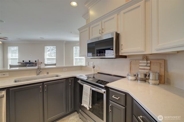 kitchen with a sink, stainless steel appliances, gray cabinets, and light countertops