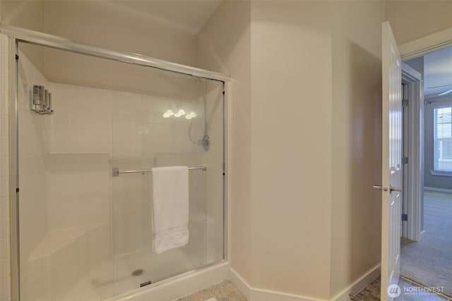 bathroom featuring a shower stall and baseboards