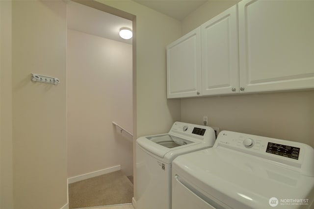 washroom featuring cabinet space, washing machine and dryer, light carpet, and baseboards