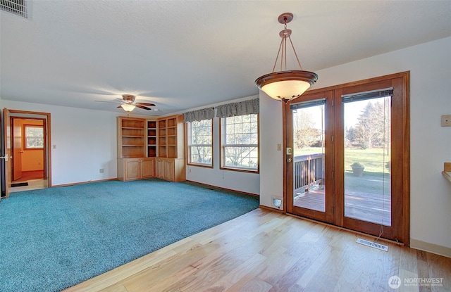 interior space with a ceiling fan, light wood-style flooring, visible vents, and baseboards