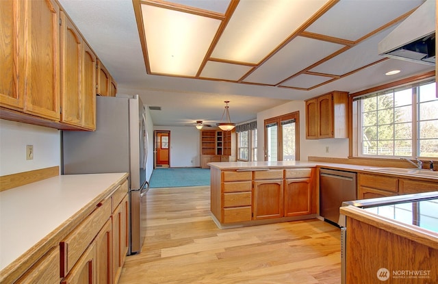 kitchen with stainless steel appliances, pendant lighting, light countertops, and a peninsula