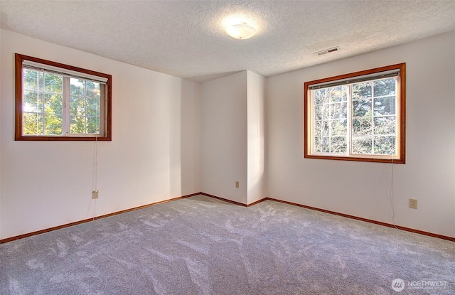 carpeted spare room featuring baseboards, visible vents, and a textured ceiling