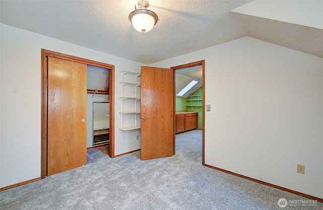 unfurnished bedroom with a closet, light colored carpet, vaulted ceiling, and a textured ceiling