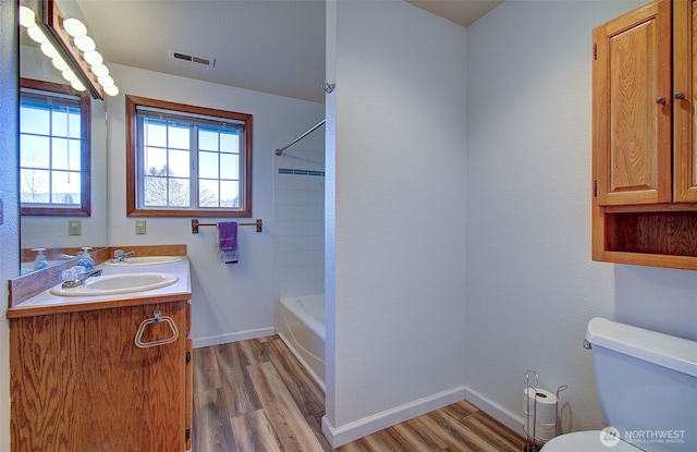 bathroom featuring a healthy amount of sunlight, a sink, visible vents, and wood finished floors