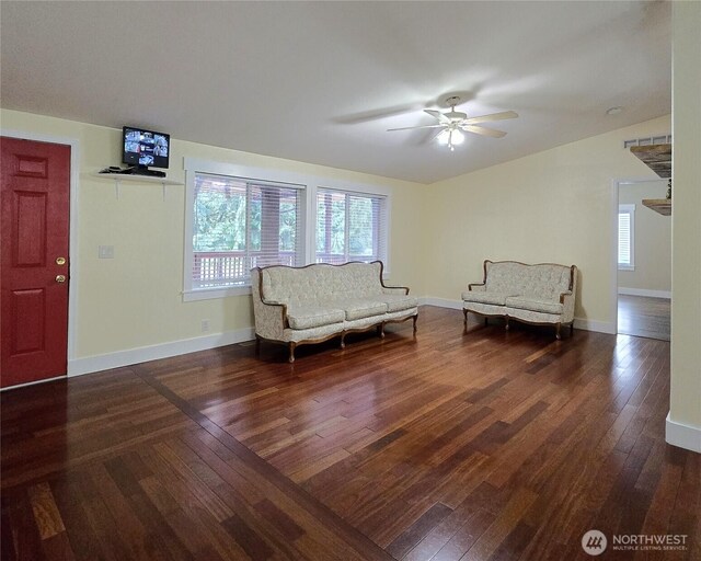 sitting room featuring a healthy amount of sunlight, dark wood-style floors, baseboards, and a ceiling fan