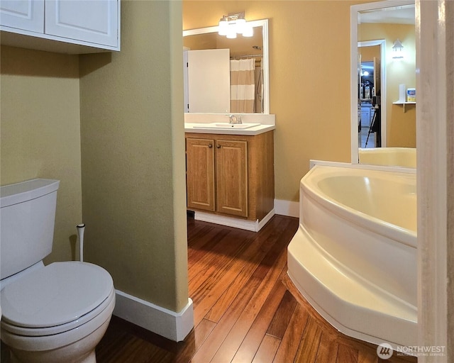 bathroom featuring wood finished floors, vanity, toilet, and baseboards