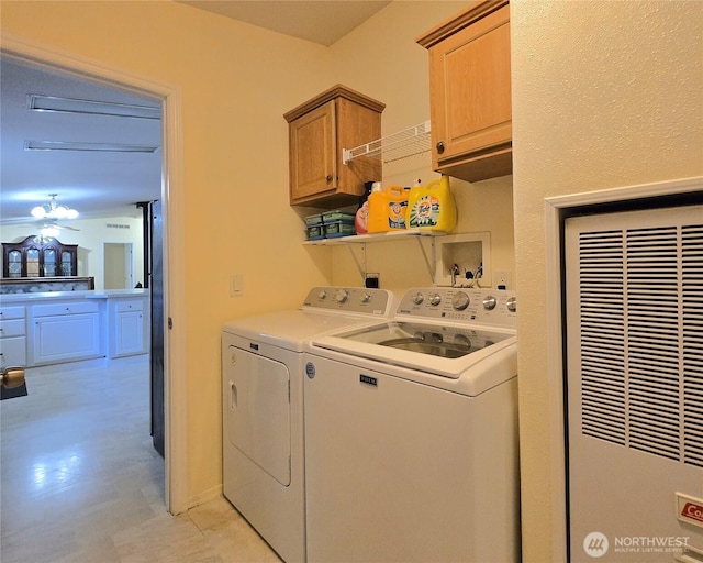 clothes washing area featuring washing machine and dryer, a heating unit, and cabinet space