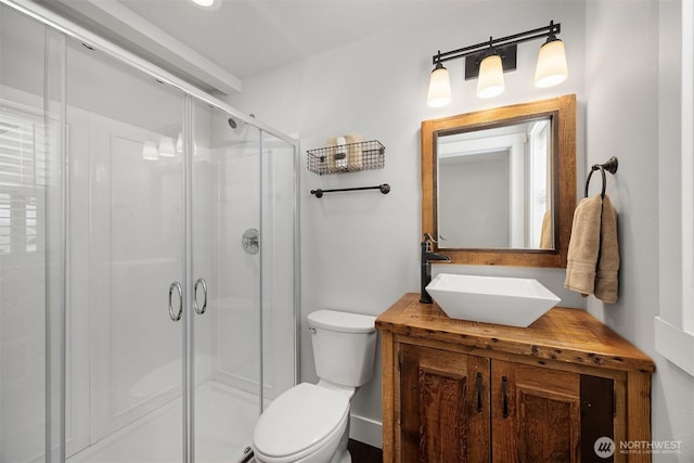 bathroom with a stall shower, toilet, and vanity