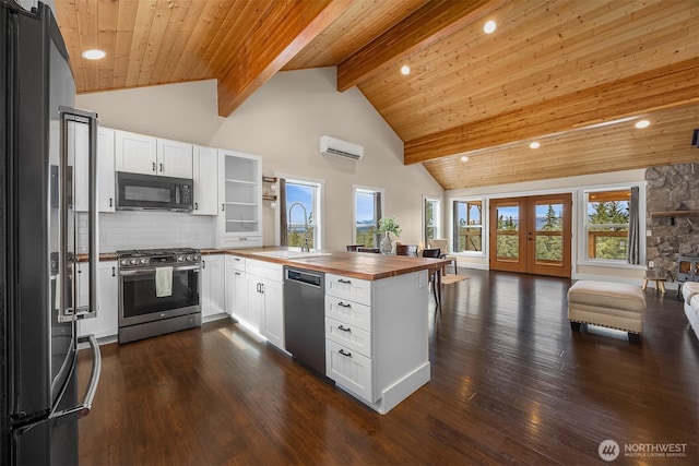 kitchen featuring a peninsula, a sink, butcher block countertops, appliances with stainless steel finishes, and open floor plan