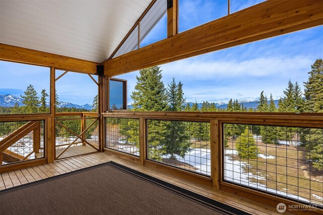 unfurnished sunroom featuring a mountain view and lofted ceiling