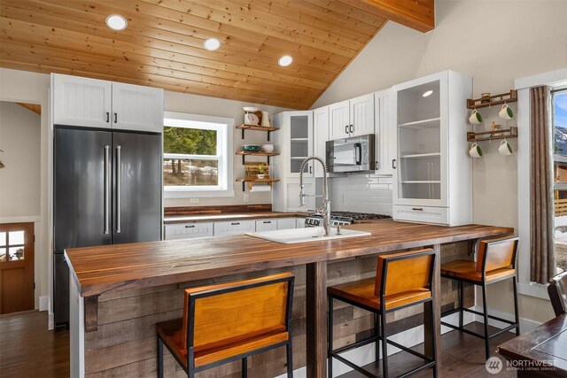 kitchen with open shelves, wood counters, lofted ceiling with beams, appliances with stainless steel finishes, and decorative backsplash