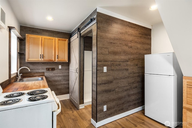 kitchen featuring light wood-style flooring, white appliances, a barn door, and a sink