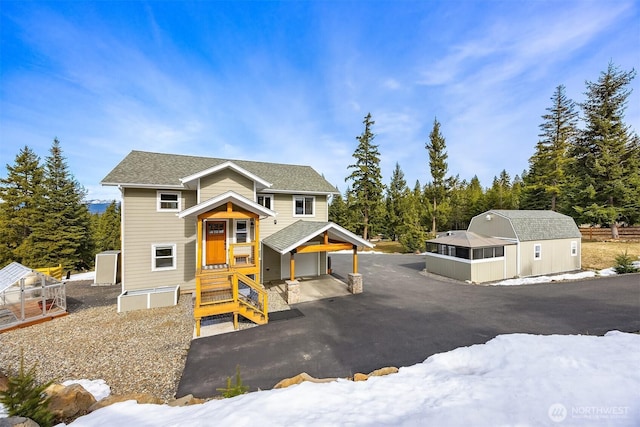 view of front of property featuring an exterior structure, an outbuilding, and a shingled roof