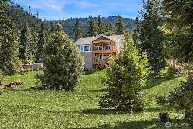 exterior space featuring a yard, a forest view, and a wooden deck