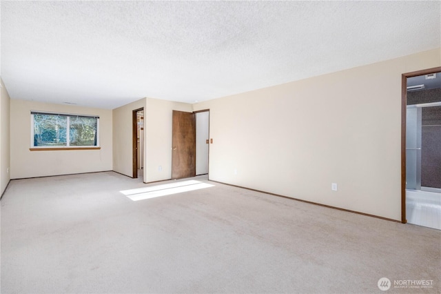 empty room with a textured ceiling and light colored carpet