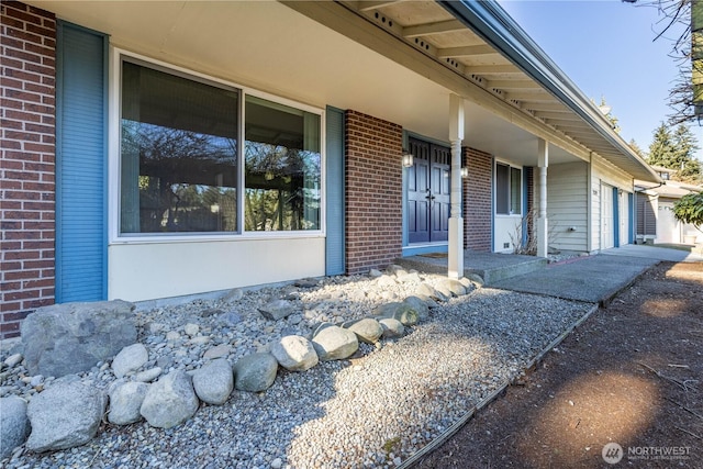 property entrance with a garage and brick siding