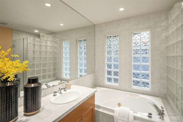 full bathroom with tiled shower, a whirlpool tub, vanity, tile walls, and recessed lighting