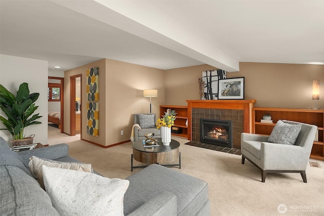 living area featuring light colored carpet, a fireplace, visible vents, baseboards, and beam ceiling