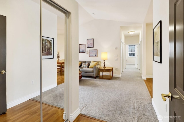 hallway featuring lofted ceiling, carpet, wood finished floors, and baseboards