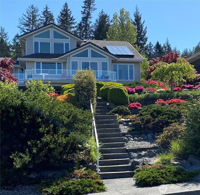 view of front facade featuring stairs and roof mounted solar panels