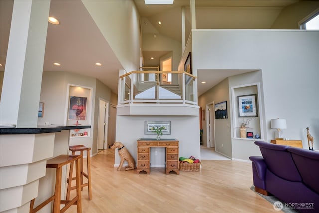 living room featuring light wood-type flooring, a towering ceiling, and recessed lighting