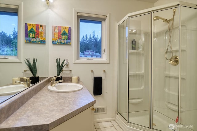 full bath with tile patterned flooring, vanity, visible vents, and a shower stall